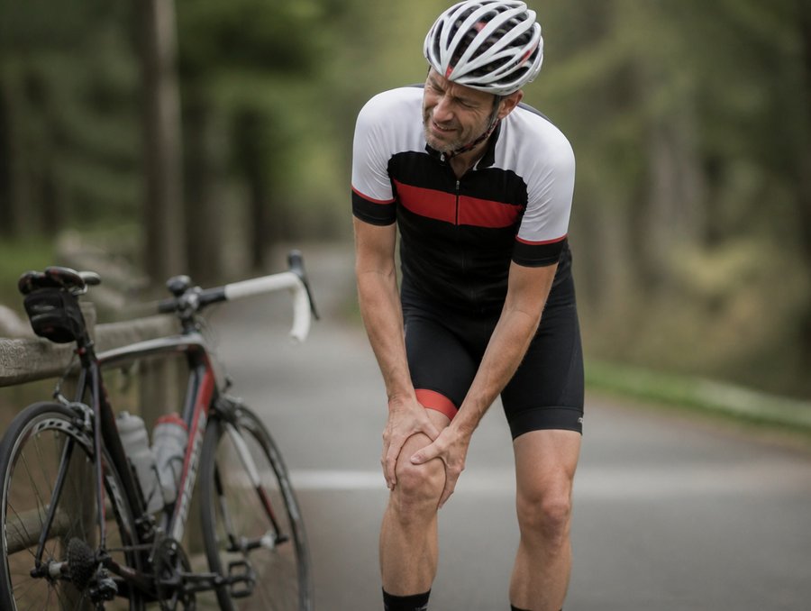 Cycliste se tenant le genou douloureux sur la route